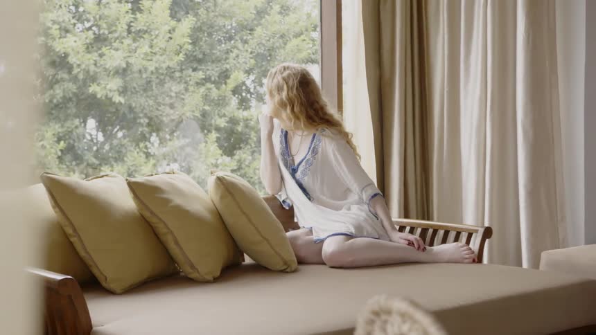 A woman relaxes on a couch with pillows