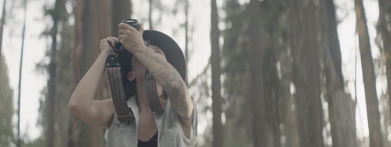 A woman takes photos in a sunny forest