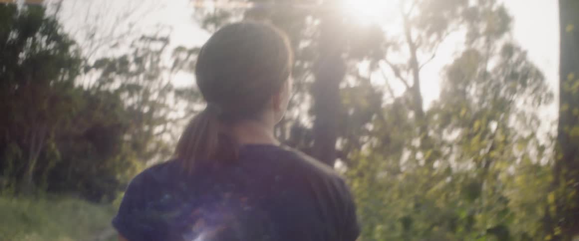 A woman walks in a forest on a sunny day
