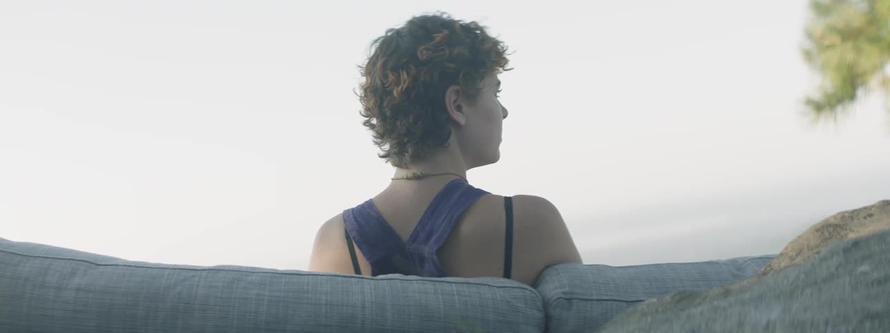 Woman is sitting on couch outside on cloudy day