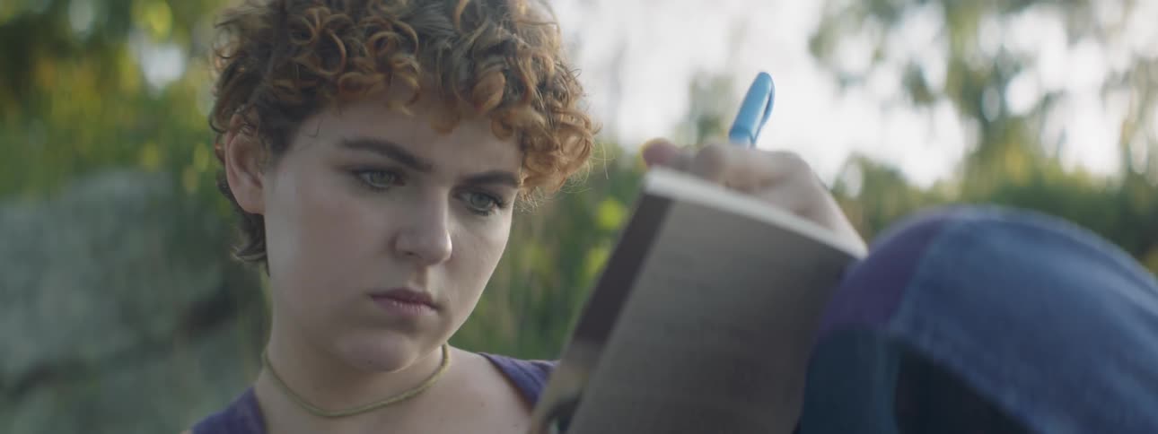 Woman sits outside reading a book