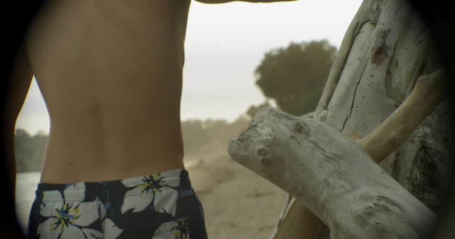 The man walks past logs on the beach