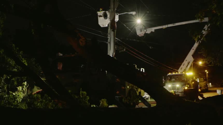 A cherry picker extends towards the power lines