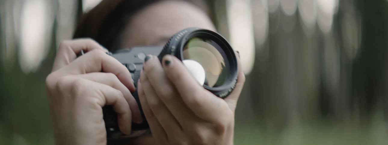 A woman is photographing outside on a sunny day