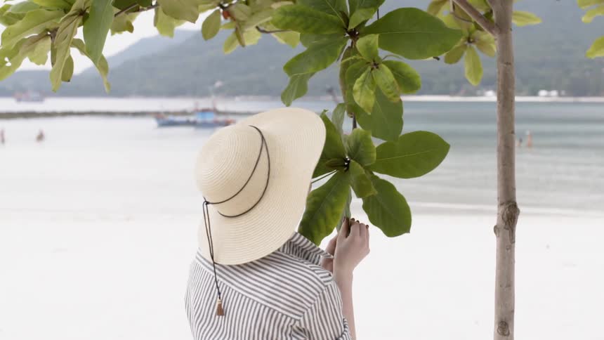 A woman smells leaves on a tree