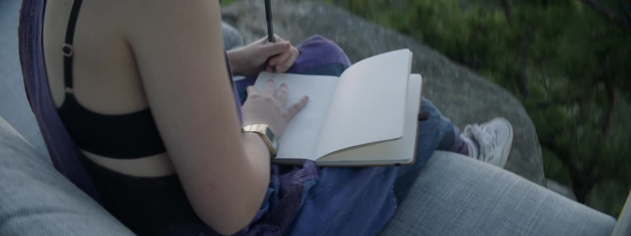 Woman writes in a notebook with her left hand