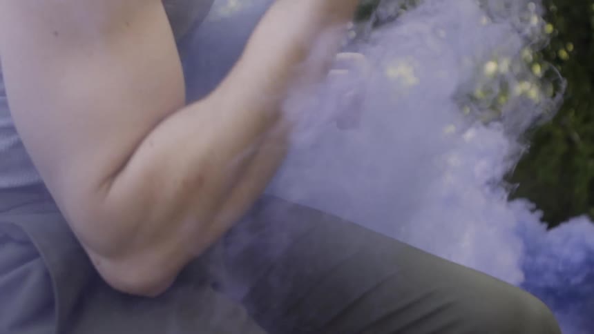 A man dances around in the purple smoke