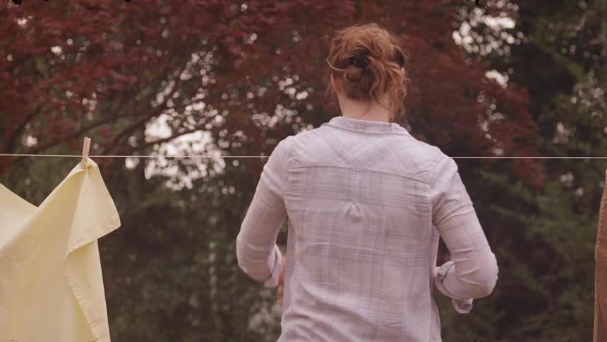 A woman lifts some clothes to hang