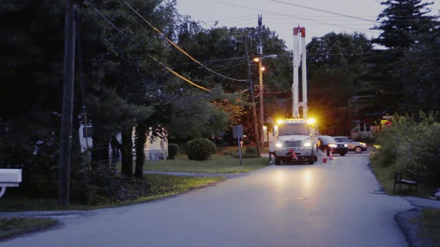 Lights flash on a utility truck surrounded by pylons