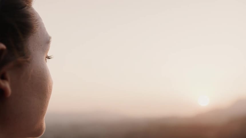 A woman stares out towards the sun