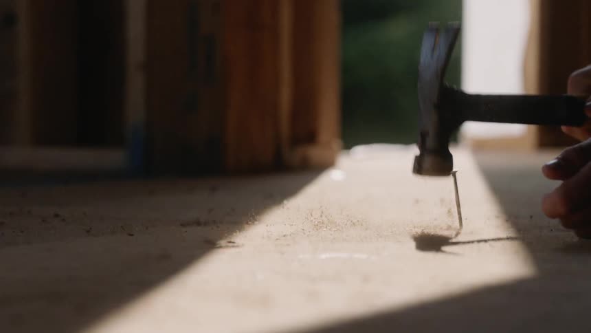A person is hitting a nail in the wood