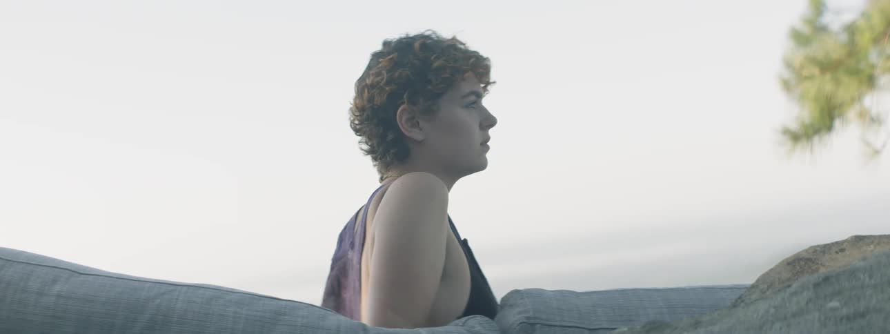 The woman is leaning on the couch on a cloudy day