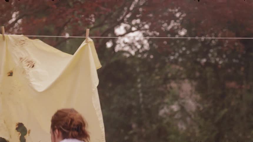 Woman removes clothes from the clothesline and folds them