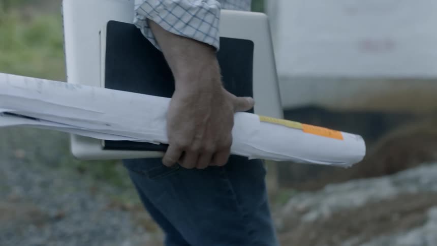 Man Looks At Blueprints For A Construction Site