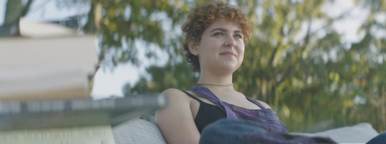 Woman blinks her eyes as she sits near a tree
