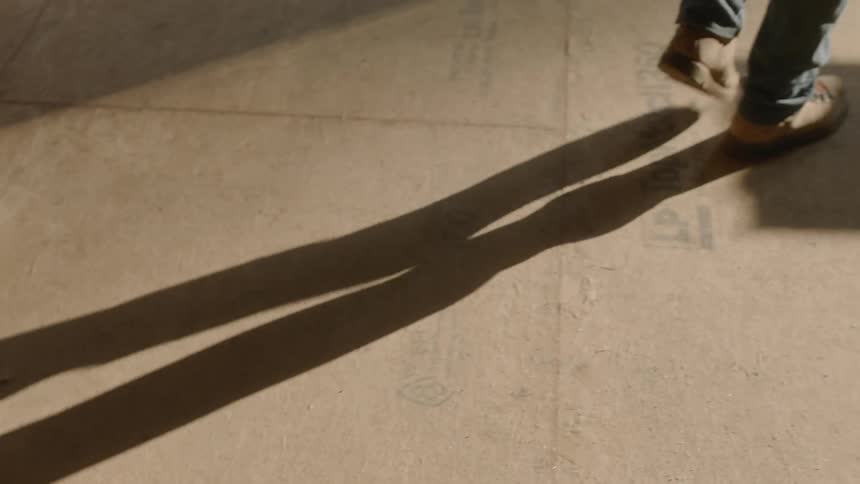 Man casts a shadow as he walks carrying a rolled scroll