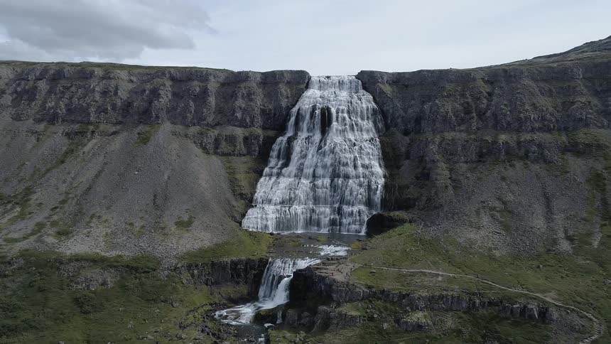 The waterfall is wide leading into a stream