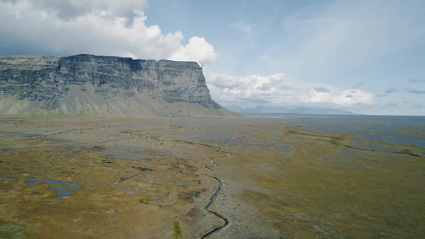 Stream flows through large flat area of land near a plateau