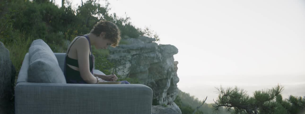 A woman is sitting on a couch on the hill