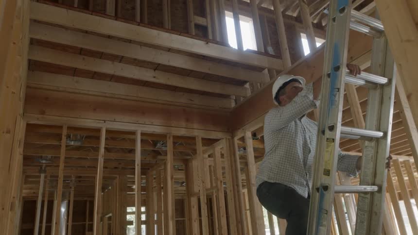 Man Looks At Blueprints For A Construction Site