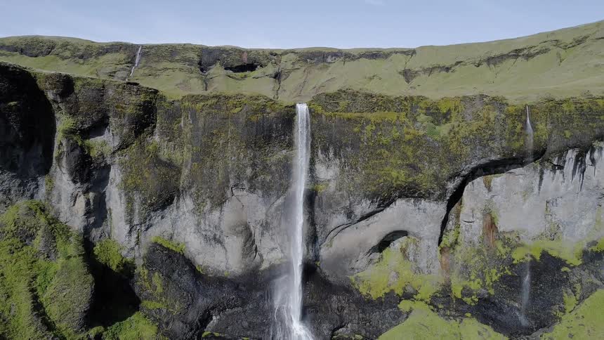 Water flows over the cliff onto the rocks below