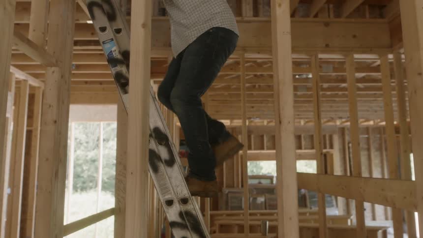 Man climbs a ladder in a building being constructed