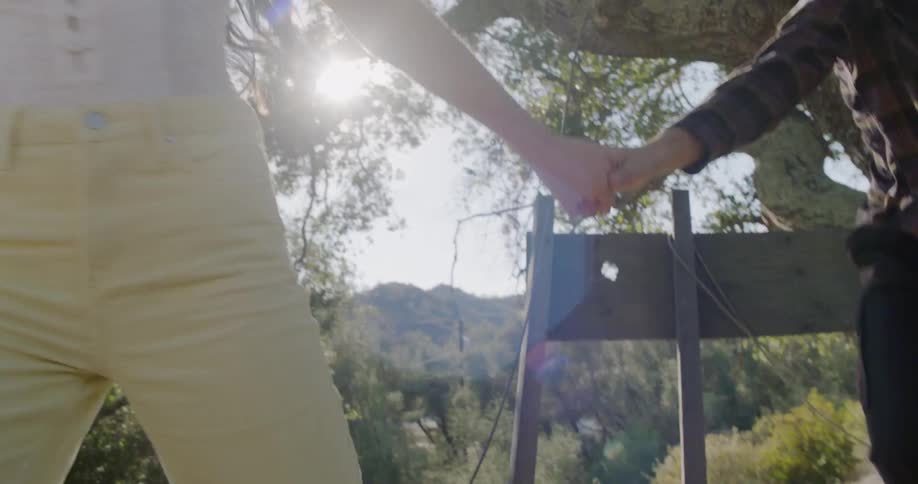 A woman helps a man stand by a tree