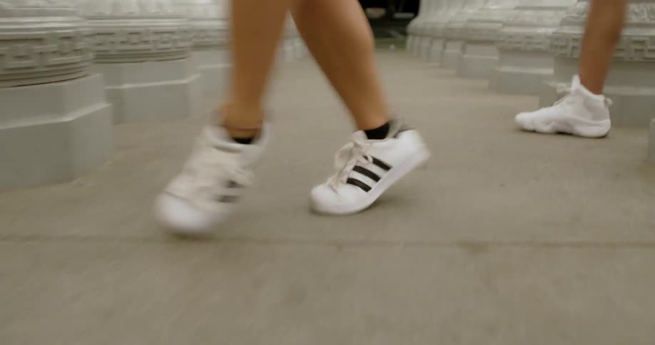Two people dance outside in between a hallway of pillars at night