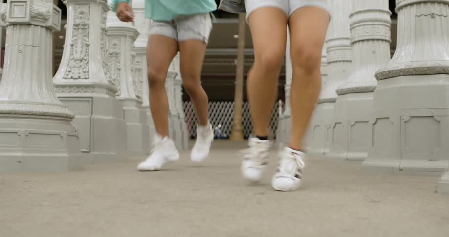 Two people dance outside in between a hallway of pillars at night