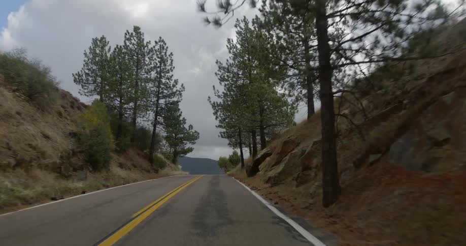 Traveling down a paved remote road towards a cloudy sky