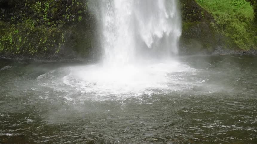 A waterfall splashes into a river