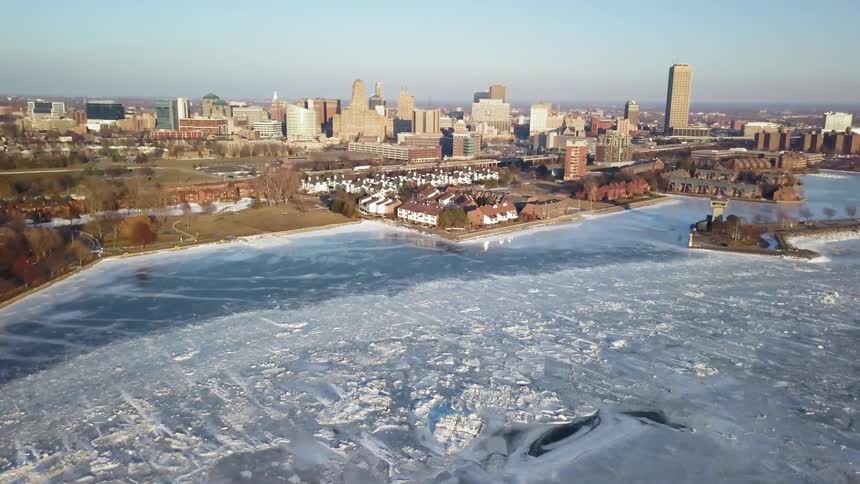 Ice is covering a waterway near a city on a sunny day