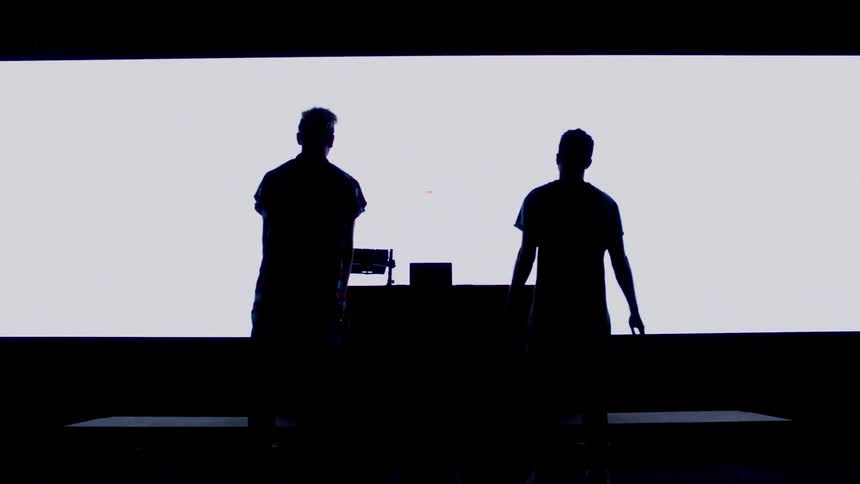 Two people walk over to a table by a screen