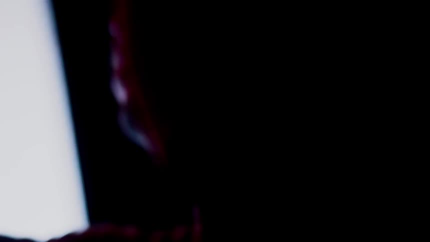 Man stands in a dark room dancing in front of a flashing screen