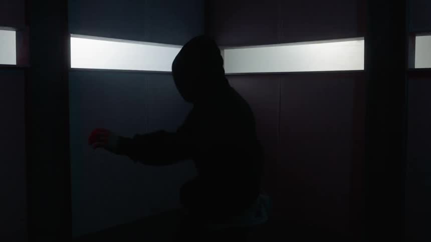 A person is jumping around dancing in the dark corner