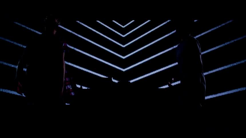 Two men dance in front of cylinder shaped lights