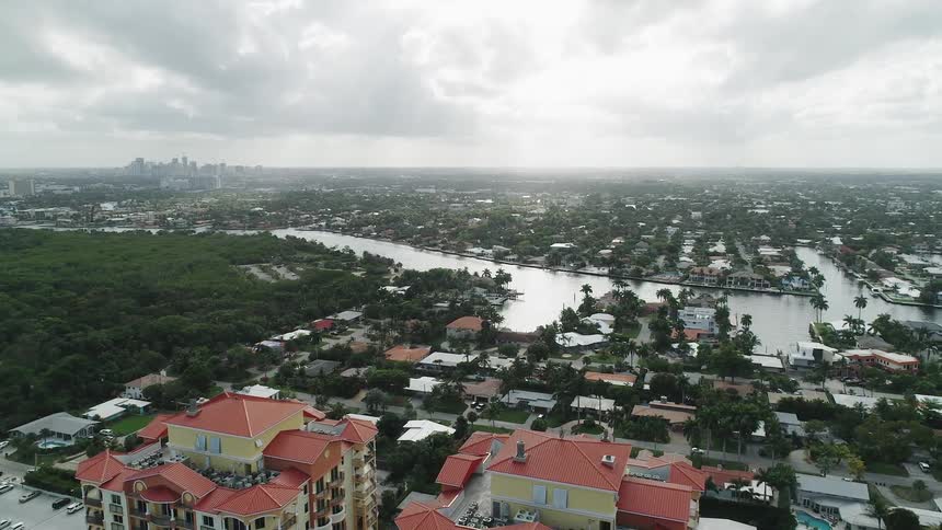 A canal runs between a neighborhood with a city skyline on the horizon
