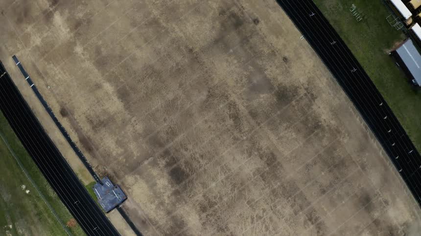 A field stripped of turf is surrounded by an outdoor running track