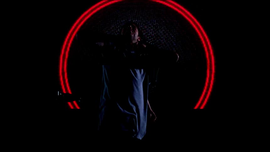 Two people dance in a room with lights on a screen