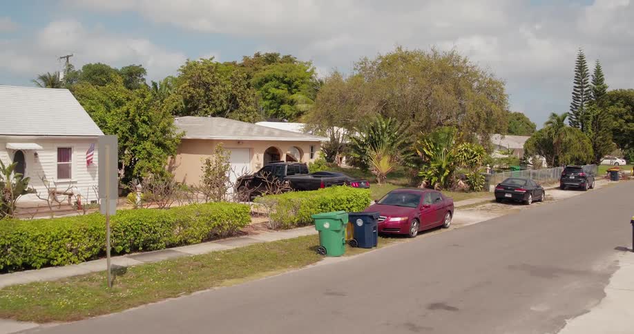 Van travels down a street past the garbage bins