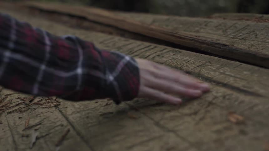 A hand clears away debris from wood
