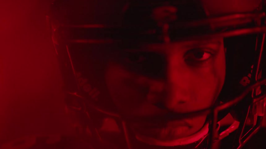 A football player is standing and staring in a room with flashing lights