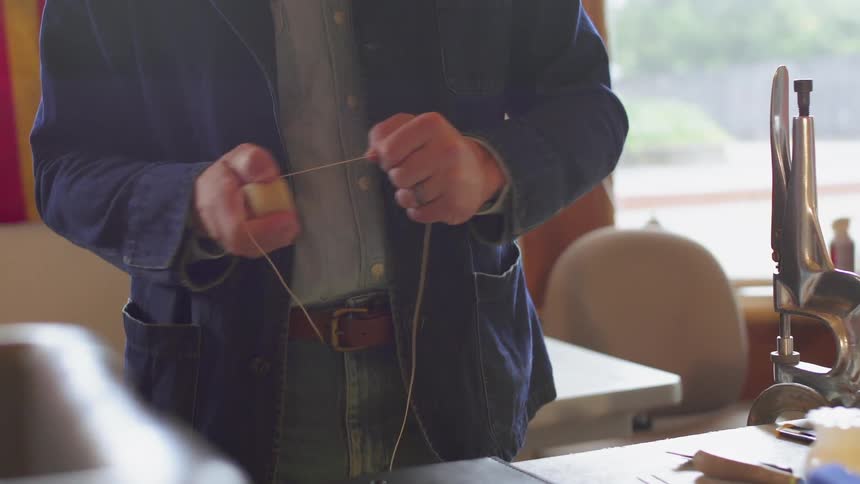 The man pulls some thread in his hands