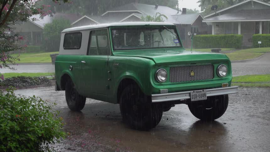 Rain falls onto a green truck in the driveway