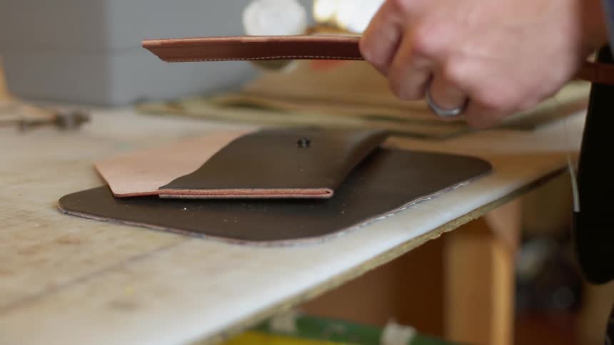 A man makes leather wallets in a workshop