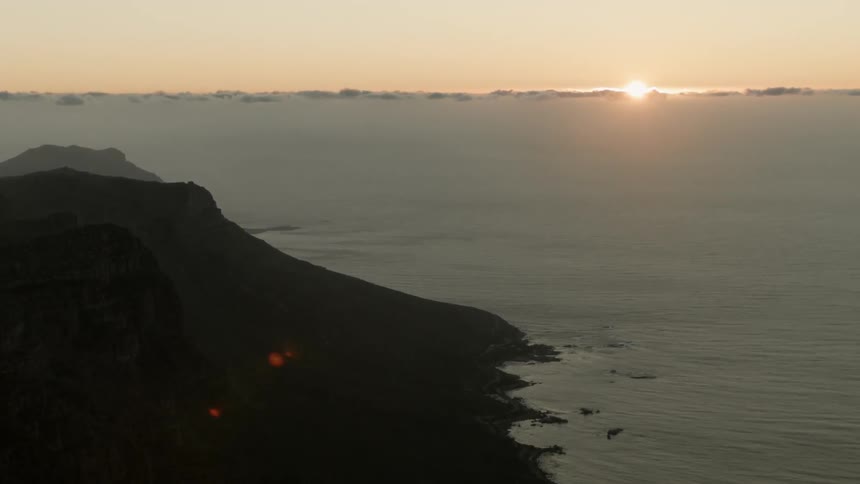 The sun sets near a mountain