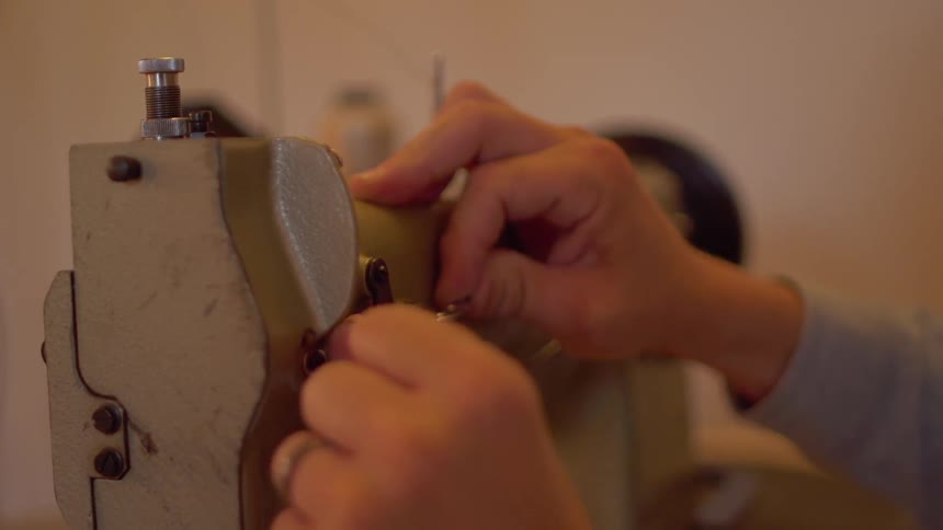A man threads a sewing machine