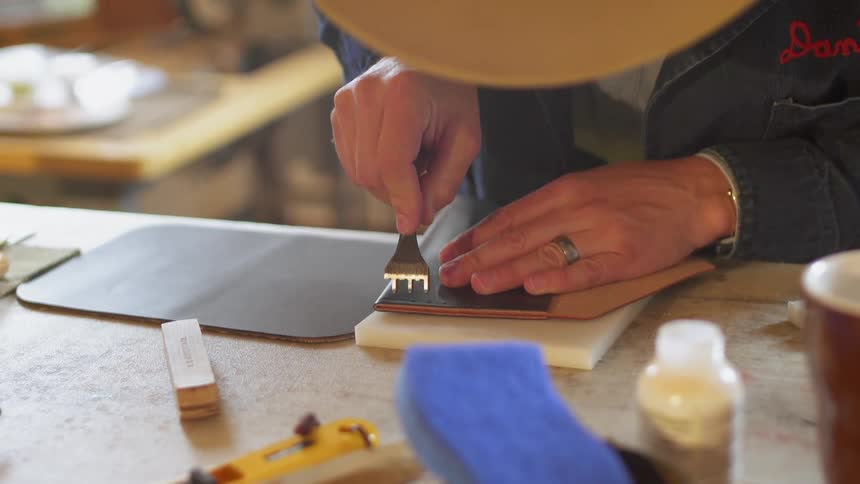 A man is working with leather on the bench