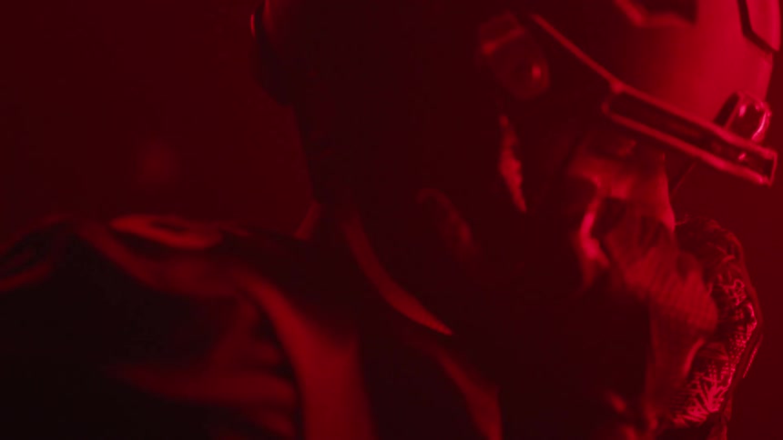 Man in football jersey puts on helmet in room with red light