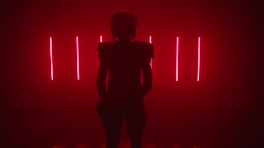 Football player is standing in room with red lights